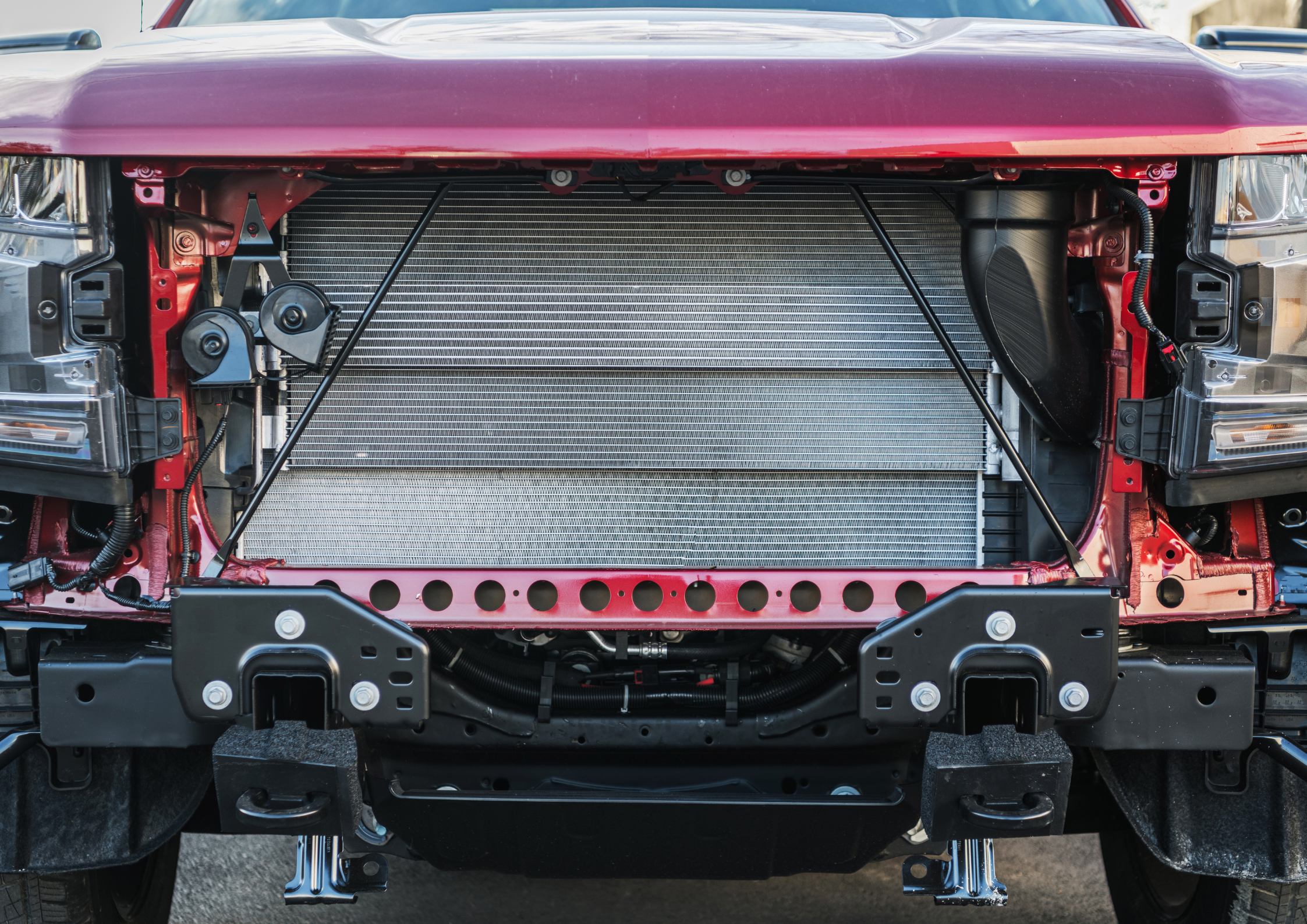 Close-up van een grote aluminium radiateur gemonteerd in de motorkap van een 4x4 terreinwagen in een werkplaats.